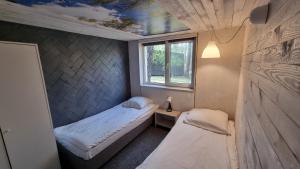 a small room with two beds and a window at Ośrodek La La Las - domki letniskowe w lesie nad jeziorem in Bytnica