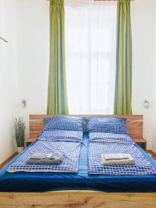 a bed with blue and white pillows and a window at Historic Old Town Home in Budapest