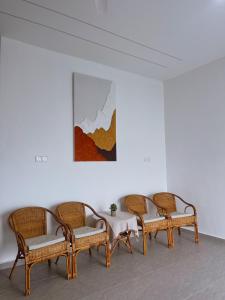 vier rieten stoelen en een tafel in een kamer bij Elonna Homestay in Jerantut