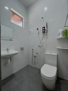 uma casa de banho branca com um WC e um lavatório em Elonna Homestay em Jerantut