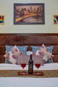 a bottle of wine and two glasses on a bed at Sonam Plaza in Ludhiana