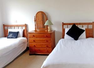 ein Schlafzimmer mit 2 Betten und eine Kommode mit einer Lampe in der Unterkunft El Martins in Miltown Malbay