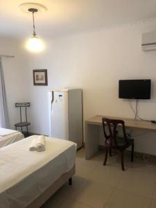 a room with a bed and a desk with a refrigerator at Quinta Da Bica D'Agua Village in Florianópolis