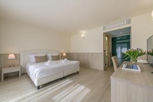 a white bedroom with a bed and a living room at Hotel Golf Inn in Lignano Sabbiadoro