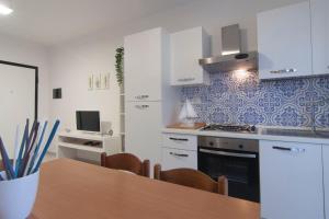 eine Küche mit weißen Schränken und einem Holztisch in der Unterkunft Appartamento Prato in Follonica