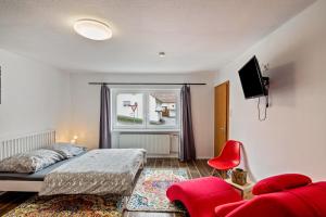 ein Schlafzimmer mit einem Bett, einem Fenster und einem roten Stuhl in der Unterkunft Vogelsberger Bett Köddingen 