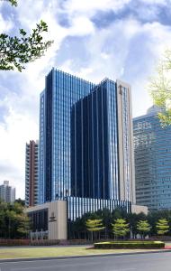 een groot blauw gebouw met bomen ervoor bij JW Marriott Hotel Shenzhen in Shenzhen
