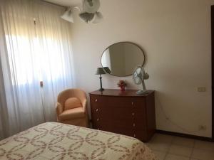 a bedroom with a dresser with a mirror and a chair at Appartamento FAB in Follonica