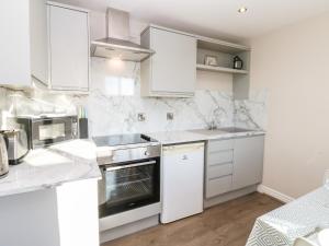 a white kitchen with white cabinets and appliances at Elder Cottage in Richmond