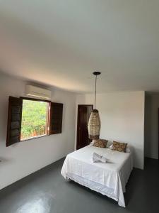 a white bedroom with a bed and a window at Pousada Villa Xaréu in Barra Grande