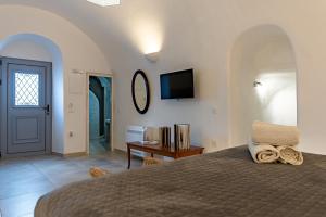 a bedroom with a bed and a tv on the wall at Argy's Luxury Caves - Red Cave in Megalochori