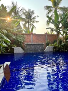 a swimming pool with blue water and palm trees at Angkor Sand Hotel in Siem Reap