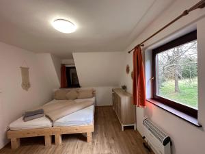 um pequeno quarto com uma cama e uma janela em Horská chata Svahová em Boleboř