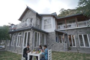 a group of people sitting at a table in front of a house at Casa De Bello, Nainital, Near Kainchi Dham in Nainital