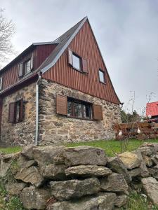 a stone house with a red roof and a stone wall at Horská chata Svahová in Boleboř
