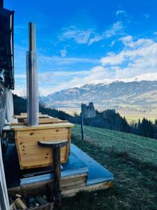 a wood stove sitting on top of a field with mountains at Landgasthof Marhube in Baldramsdorf