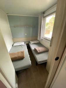 Habitación pequeña con 2 camas y ventana en Mobil home - Clim, TV - Camping Falaise Narbonne Plage 4 étoiles - 010, en Narbonne-Plage