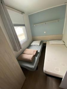 una piccola camera con due letti e una finestra di Mobil home - Clim, TV - Camping Falaise Narbonne Plage 4 étoiles - 010 a Narbonne-Plage