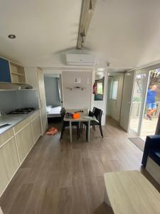 una cocina y comedor con una mesa en una caravana en Mobil home - Clim, TV - Camping Falaise Narbonne Plage 4 étoiles - 010, en Narbonne-Plage