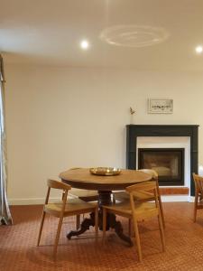 een tafel en stoelen in een kamer met een open haard bij Gîte de charme XIXe in Grand-Champ