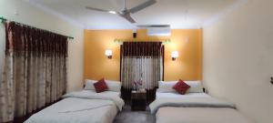 3 camas en una habitación con paredes y cortinas de color naranja en Hotel Rhino Land, Sauraha, en Sauraha