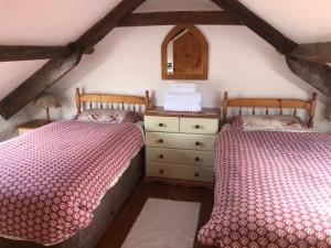 a bedroom with two beds and a dresser with a mirror at The Granary in Bridgend