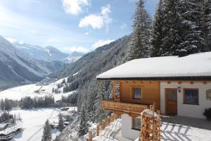 una cabaña en las montañas con nieve en el techo en Ferienhaus Innerzarge, en Tux