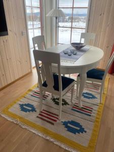 une table à manger blanche et des chaises sur un tapis dans l'établissement Tällberg, utsikt över Siljan, à Leksand