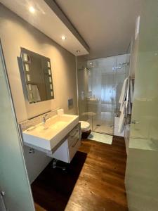 a bathroom with a white sink and a shower at 145 on Main - Legacy Green Point in Cape Town