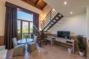Sala de estar con escalera, mesa y TV en Hotel Golf Inn, en Lignano Sabbiadoro