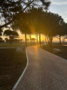 un sentiero di mattoni in un parco con alberi e il tramonto di Boo_Apartment a Durrës Altre 5 foto