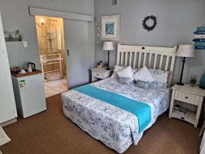 Umuzi Guest House في خليج ريتشاردز: غرفة نوم بسرير لحاف ازرق وبيض