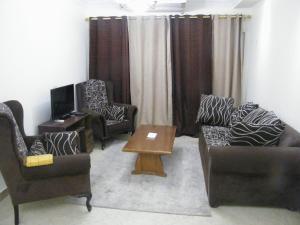 uma sala de estar com duas cadeiras e uma mesa em Mohandeseen apartment المهندسين عائلات em Cairo