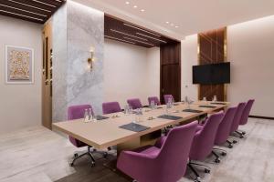 une salle de conférence avec une grande table et des chaises violettes dans l'établissement Velero Hotel Doha Lusail, à Doha