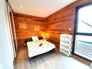 1 dormitorio con 1 cama en una habitación con paredes de madera en Sublime villa 9 pers- 5chb-pisicne-wifi, en Le Poinçonnet