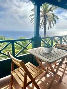 stół i krzesła na balkonie z palmą w obiekcie Villa Media Luna con vistas a La Palma by Alterhome w mieście La Galga