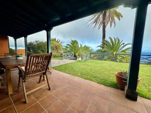 een veranda met een houten bank en een tafel bij Villa Media Luna con vistas a La Palma by Alterhome in La Galga