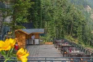 a restaurant on a wooden deck with tables and chairs at Mahasu House in Shimla