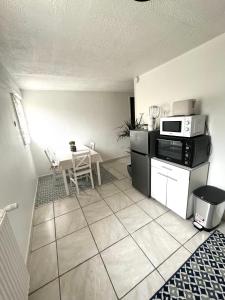 eine kleine Küche mit einem Tisch und einer Mikrowelle in der Unterkunft T2 La roseraie in Chambéry