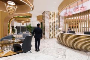 a man in a suit walking through a lobby at Velero Hotel Doha Lusail in Doha