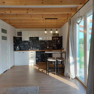 una cucina con armadi bianchi e un tavolo con sgabelli di Domek letniskowy Słoneczny Zakątek a Frombork