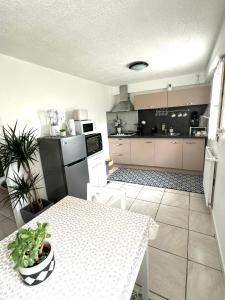 eine Küche mit einem weißen Tisch und eine Küche mit einem Kühlschrank in der Unterkunft T2 La roseraie in Chambéry
