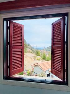 an open window with a view of a house at Maryloo Country House in Kakopetria