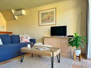 a living room with a blue couch and a tv at Riverview Holiday Apartment 92 - Kalbarri WA in Kalbarri
