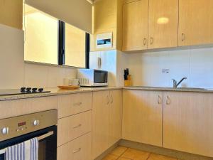 a kitchen with wooden cabinets and a microwave at Riverview Holiday Apartment 92 - Kalbarri WA in Kalbarri