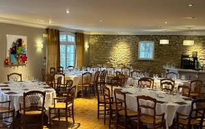 une salle remplie de tables et de chaises avec des nappes blanches dans l'établissement Logis Hôtel Restaurant La Sommellerie, à Châteauneuf-du-Pape