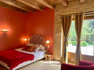 ein Schlafzimmer mit einer roten Wand, einem Bett und einem Fenster in der Unterkunft Domaine de Pech Mortier in Marcillac-Saint-Quentin