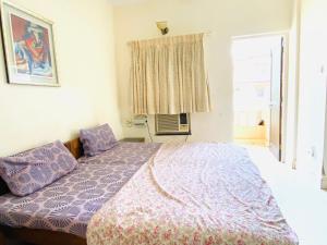 a bedroom with a bed and a window at Highland Beach Apartments Goa in Baga