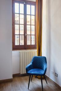 una silla azul en una habitación con ventana en URBANA 37 Maison, en Roma