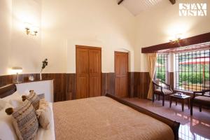 1 dormitorio con 1 cama, 1 silla y 1 ventana en StayVista at Wyncroft Bungalow with Free Breakfast & Pet Friendly Home, en Kotagiri